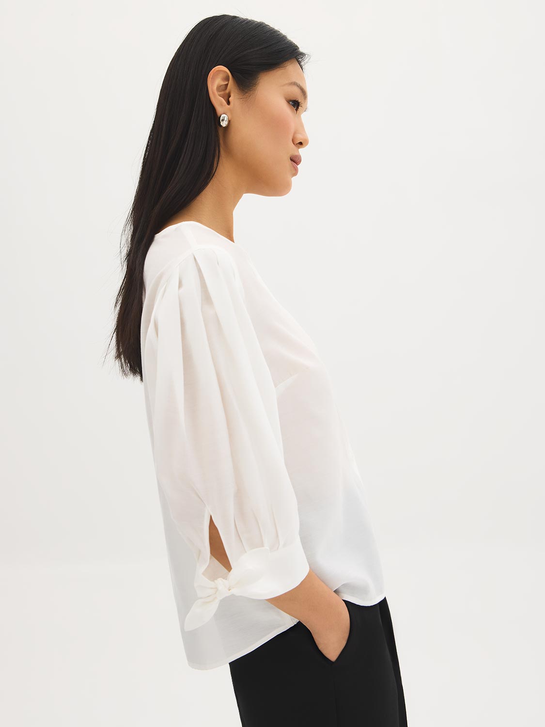 Button-front blouse in snow white with tie cuffs and pleated sleeves by Suzy Shier.