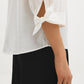 Button-front blouse in snow white with tie cuffs and pleated sleeves by Suzy Shier.