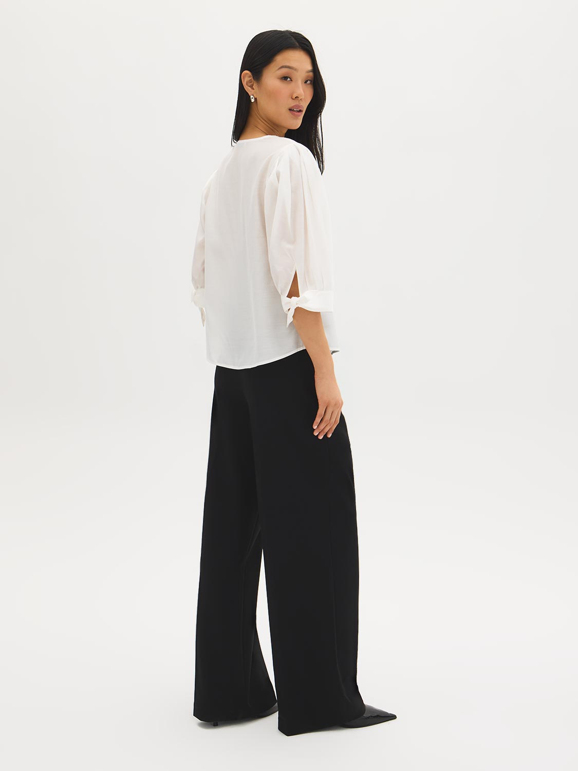 Button-front blouse in snow white with tie cuffs and pleated sleeves by Suzy Shier.