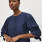 Button-front blouse in snow white with tie cuffs and pleated sleeves by Suzy Shier.