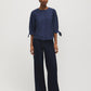 Button-front blouse in snow white with tie cuffs and pleated sleeves by Suzy Shier.