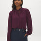Winetasting Swiss Dot Peplum Blouse with Ruffle Neck - Woman Wearing Textured Blouse with Self-Tie - Suzy Shier